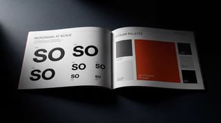 Hands browsing a brand guidelines book at a desk